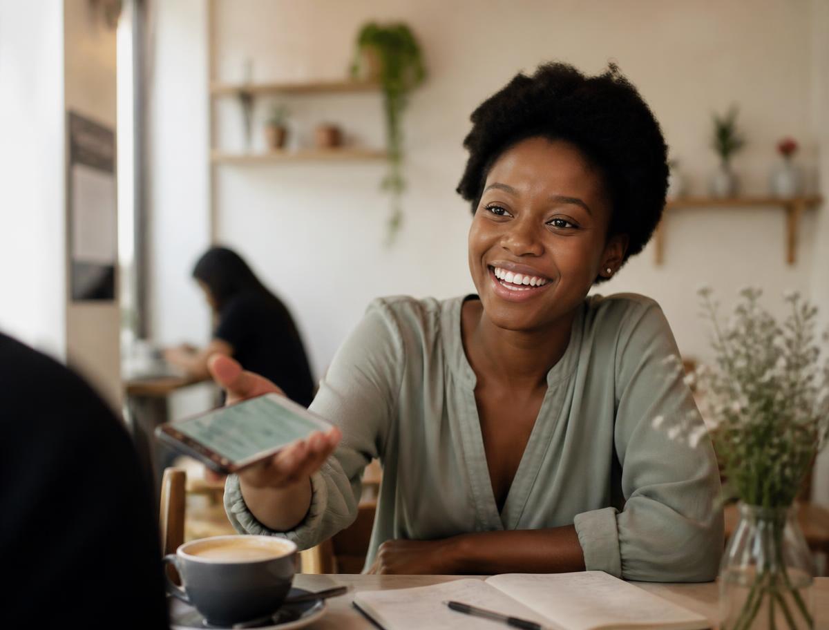 Young entrepreneur sharing her NexaCash referral link from a phone in a café